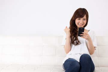 ソファでスマホを見る女性