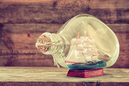 image of decorative boat in the bottle on wooden table. nautical concept