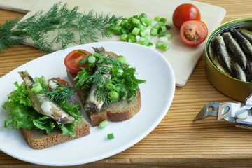 sprats, bread, onion and tomatoes on a table