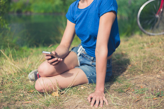 Young woman using smart phone by water in park