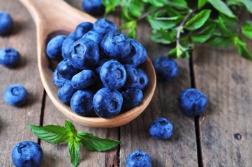 Organic fresh blueberries with peppermint on a wooden background