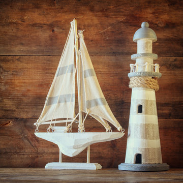old vintage wooden lighthouse and sailing boat on wooden table