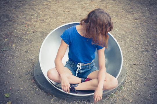 Young woman sitting in big metal dish