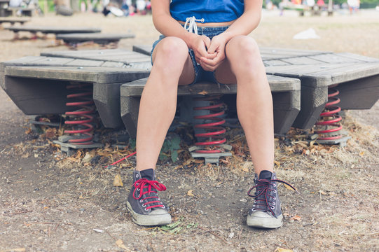 Young woman sitting on playground equipment outside