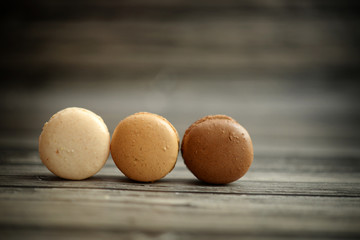 Three macaroons in a line on dark wood background
