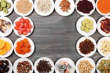 Different products on saucers on wooden table, top view