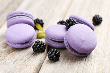 Obraz na płótnie Canvas Tasty purple macarons with blackberry on grey wooden background