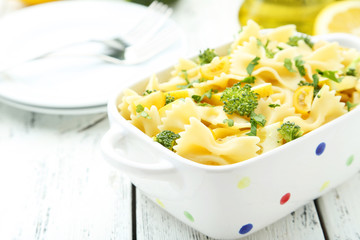Delicious pasta with with broccoli in bowl on white wooden backg