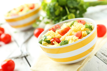 Delicious pasta in bowl on white wooden background