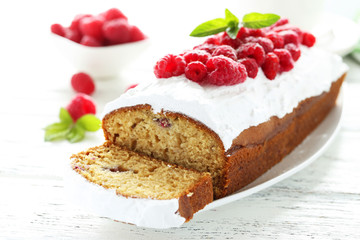 Raspberry cake on plate on white wooden background