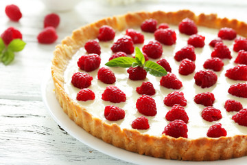 Sweet tart cake with raspberries on white wooden background