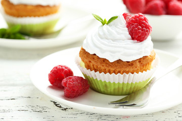 Raspberry cupcakes on plate on white wooden background
