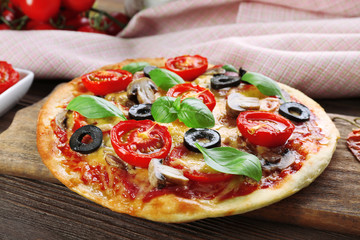Tasty pizza with vegetables and basil on table close up