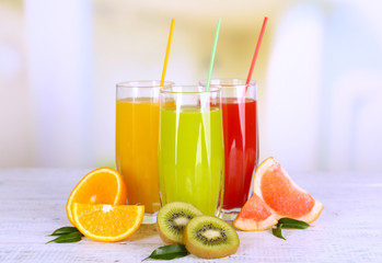 Naklejka na ściany i meble Glasses of different juice with fruits and mint on bright background