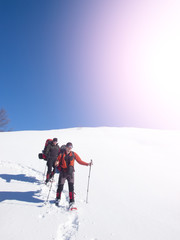 Men go snowshoeing in the mountains in the snow.