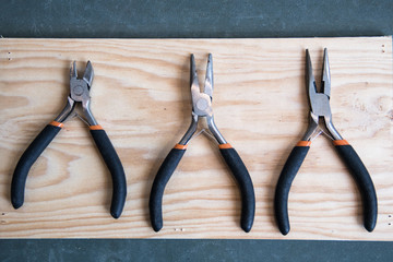 Composition of three small pincers on a wooden background
