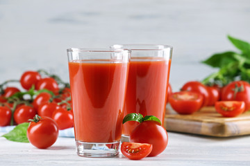 Glasses of tomato juice with vegetables on wooden table close up