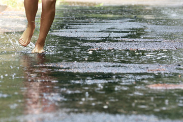 Woman walking barefoot through puddle outdoors