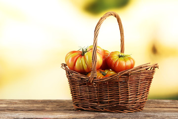 Green tomatoes in basket on bright background