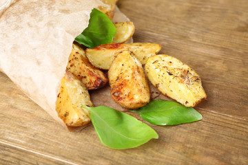 Baked potatoes in parchment on wooden table, closeup