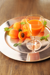 Glass of apricot juice and fresh fruits on table close up