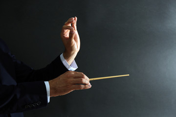 Music conductor hands with baton on black background
