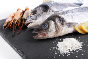 Fresh fishes and shrimps with spices  on gray background