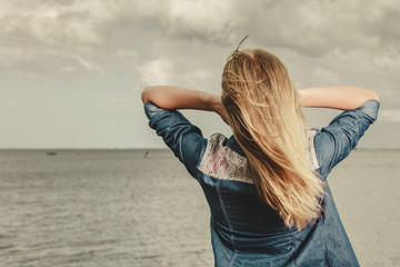 Rear view of young blond woman looking at the ocean