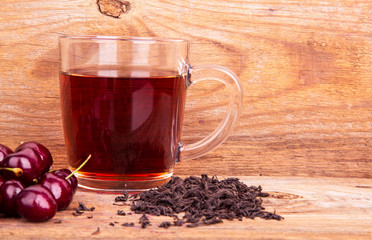 cup of tea and sweet cherry on a wooden background