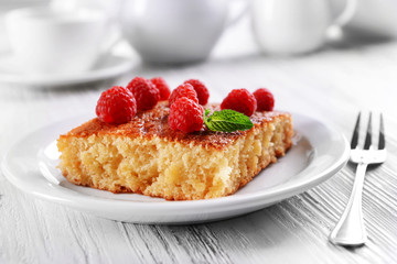 Fresh pie with raspberry in white plate on wooden table, closeup