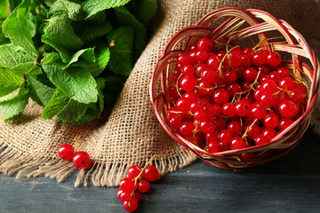 Ripe red currant in wicker basket on wooden background