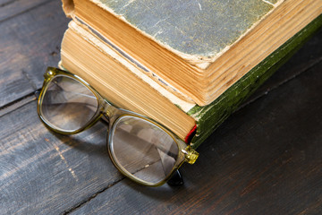 Vintage reading glasses and the book on wooden background