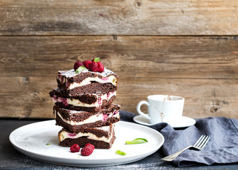 Brownies-cheesecake tower with raspberries on white plate