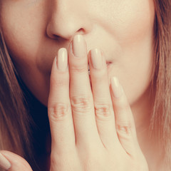 Shy speechless human covering mouth with hand.