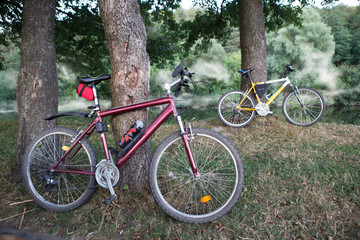 Fototapeta premium Mountain bikes on the bank of the river in mist