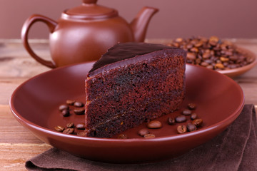 Delicious chocolate cake with coffee beans on plate on table close up