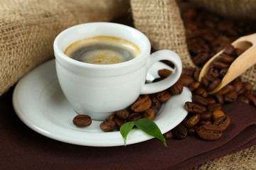 Cup of coffee with beans on table close up