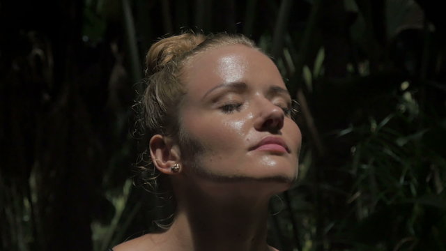 Beautiful model standing in the jungle scene, thinking while her eyes searches for the ray of sun, shadows falling on the rest of her body creating a warm atmosphere.
