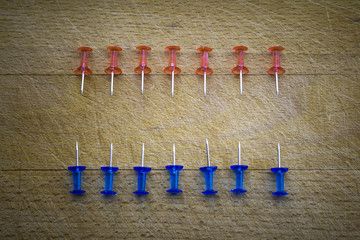 Red and blue pins on a wooden table