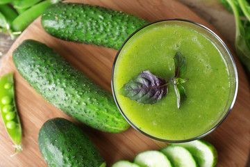 Glass of green healthy juice with spinach and cucumbers on table close up