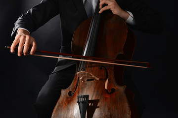 Man playing on cello on dark background