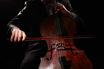 Man playing on cello on dark background © Africa Studio