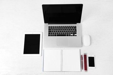 Office supplies and gadgets on white table, top view