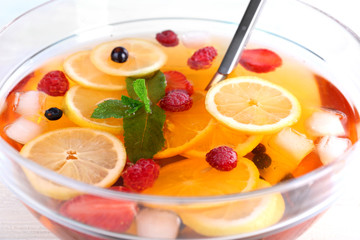 Fruity punch in glass bowl on wooden table, closeup