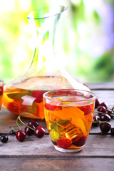 Punch with berries in glassware on wooden table on light blurred background