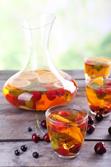 Punch with berries in glassware on wooden table on light blurred background