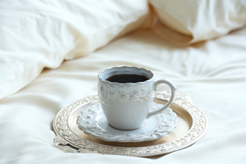 Morning cup of coffee on comfortable bed in bedroom
