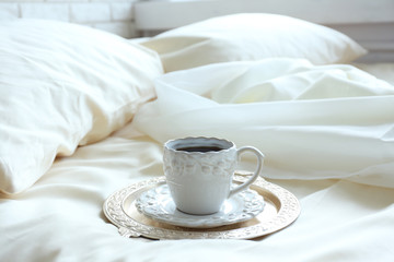 Fototapeta na wymiar Morning cup of coffee on comfortable bed in bedroom