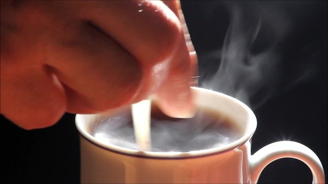 dampfender kaffee in kaffeetasse wird mit l&ouml;ffel umger&uuml;hrt, nahaufnahme

