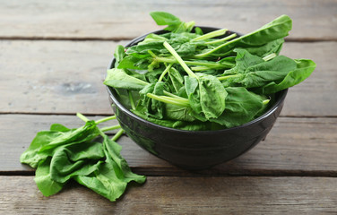 Bowl of fresh spinach leaves on wooden background
